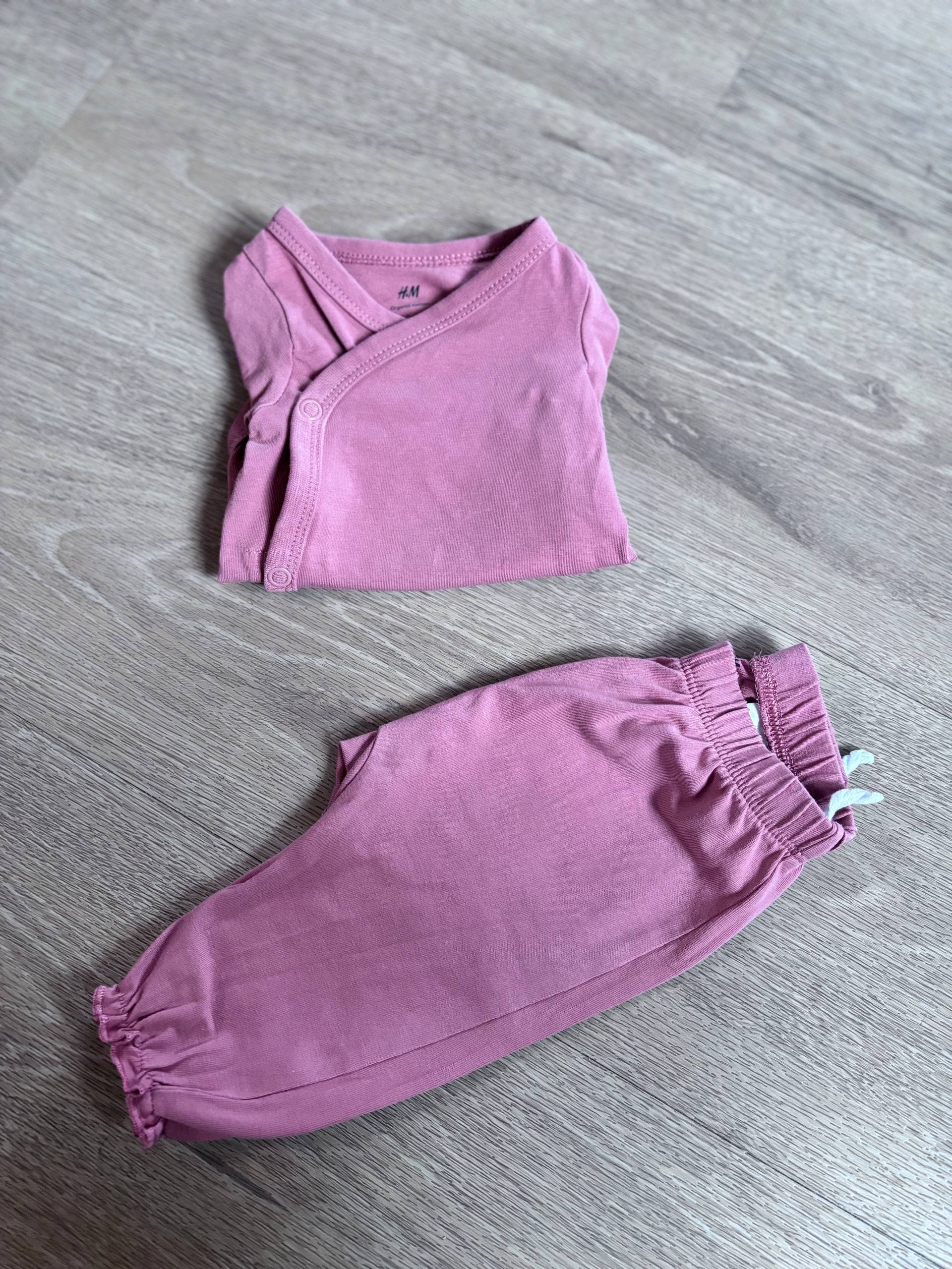 vijoličen komplet bodyja in hlač na leseni površini